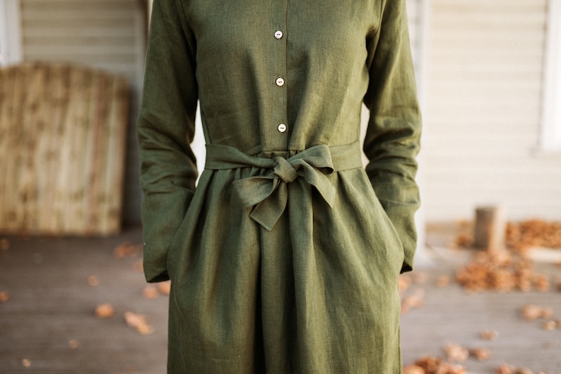 May include: A long-sleeved, green linen dress with a button-up front and a self-tie belt at the waist.