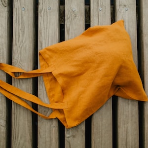 May include: A mustard yellow tote bag made of linen fabric with two handles.