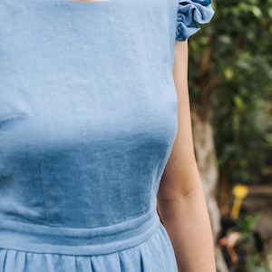 Puede incluir: Un vestido de lino azul claro con cuello redondo y mangas abullonadas.
