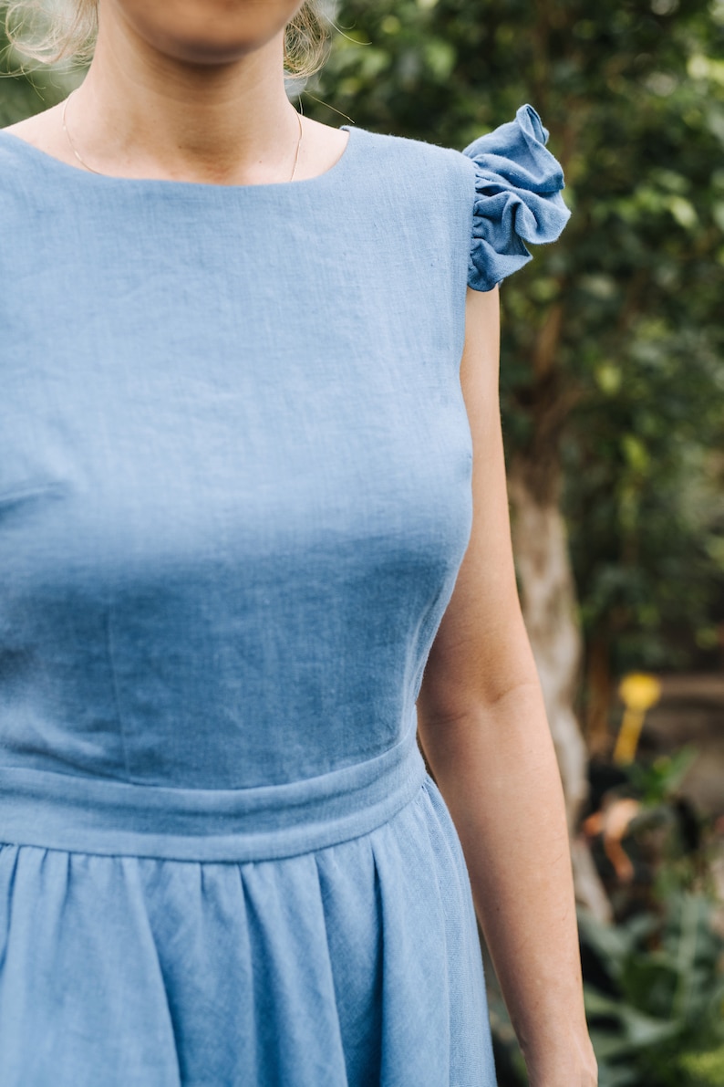 Puede incluir: Un vestido de lino azul claro con cuello redondo y mangas abullonadas.
