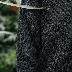 K&ouml;nnte beinhalten: Nahaufnahme eines dunkelgrauen Strickpullovers mit Rippenstruktur.