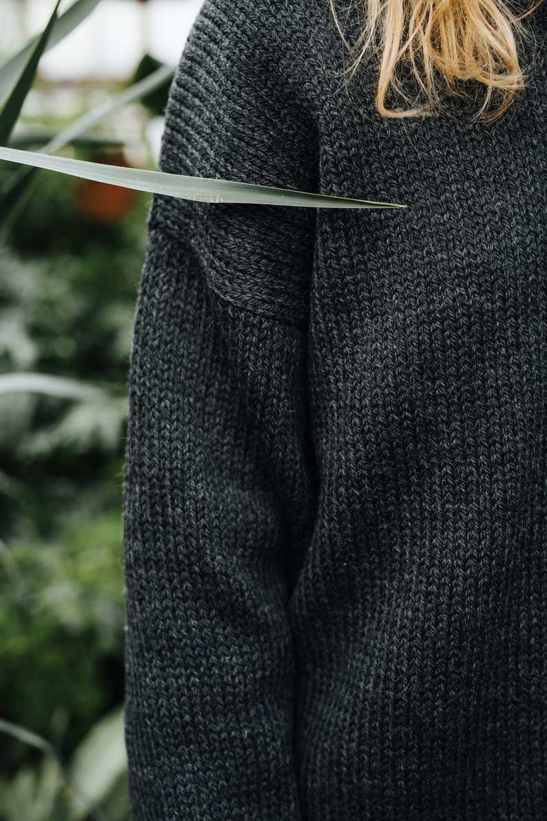 K&ouml;nnte beinhalten: Nahaufnahme eines dunkelgrauen Strickpullovers mit Rippenstruktur.