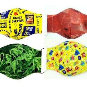 Puede incluir: Cuatro mascarillas con diseños únicos. Una mascarilla presenta un fondo amarillo con la marca Spam y texto. Otra muestra un patrón de carne cruda. Una tercera mascarilla tiene hojas verdes de cannabis, y la última tiene un fondo amarillo con ilustraciones de monstruos coloridos.