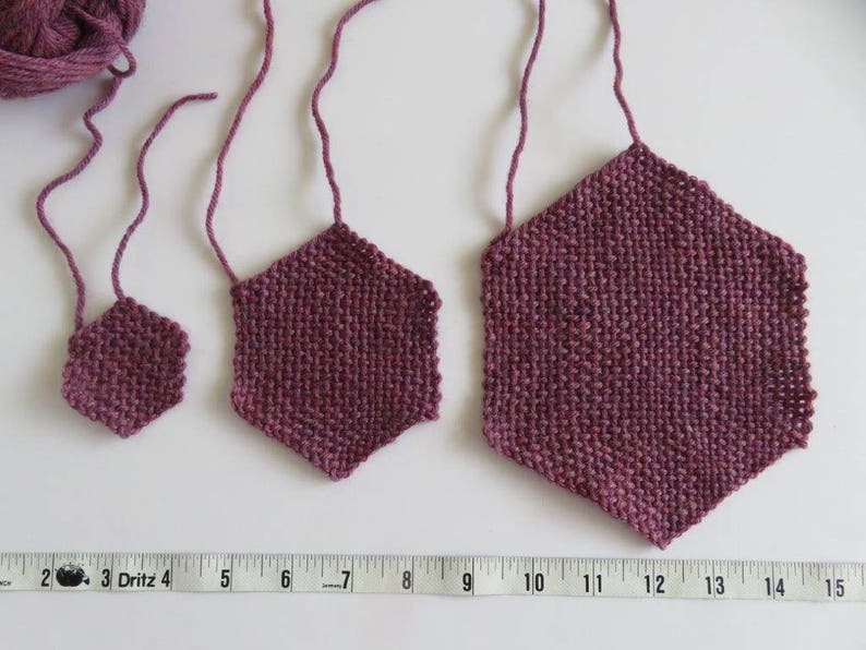 May include: Three crocheted hexagons in different sizes, all in a deep burgundy color. The hexagons are hanging from a white surface.