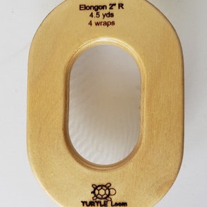 May include: A wooden oval-shaped loom with a large hole in the centre. The loom is labelled "Elongon 2" R 4.5 yds 4 wraps" and has the Turtle Loom logo on the bottom.
