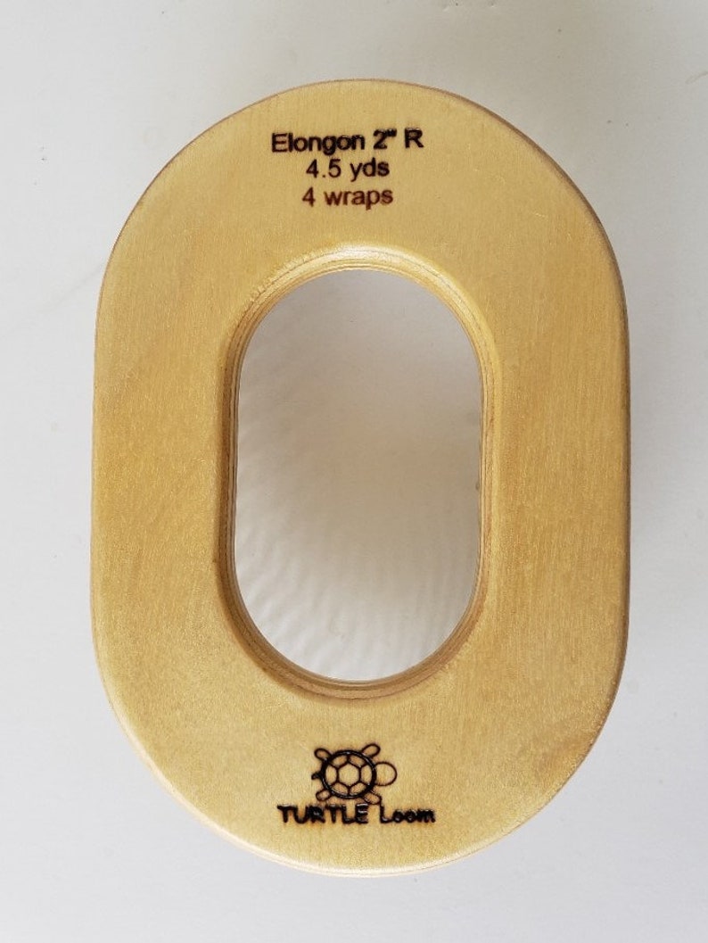 May include: A wooden oval-shaped loom with a large hole in the centre. The loom is labelled "Elongon 2" R 4.5 yds 4 wraps" and has the Turtle Loom logo on the bottom.
