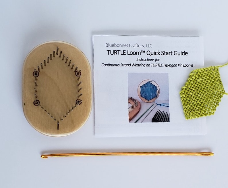 May include: A wooden hexagon-shaped loom with a set of metal pins. The loom is used for weaving with yarn. A green woven piece is shown in the background. The text on the card reads "TURTLE Loom&trade; Quick Start Guide Instructions for Continuous Strand Weaving on TURTLE Hexagon Pin Looms".