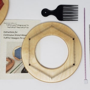 May include: A craft kit with a wooden hexagon pin loom, a black pick comb, a purple knitting needle, and a silver needle. The kit includes instructions for continuous strand weaving. A partially completed weaving project is also visible.