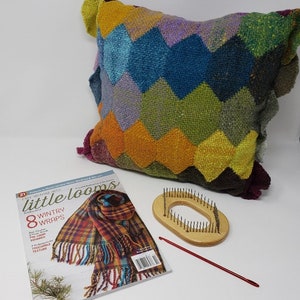 May include: A colourful woven cushion with a chevron pattern, a magazine titled "little looms" with a woven scarf on the cover, a wooden loom with a circular opening, and a red crochet hook.