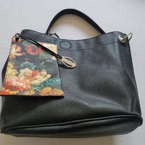 May include: Black leather tote bag with a floral print pouch attached. The bag has a silver oval tag with the word "Croco" on it.