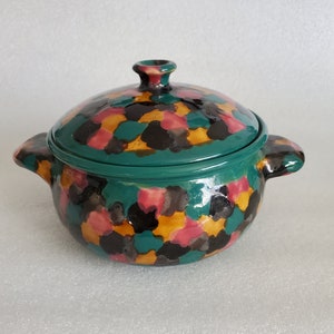 May include: A green ceramic casserole dish with a lid. The dish has a speckled design with black, pink, and yellow accents.