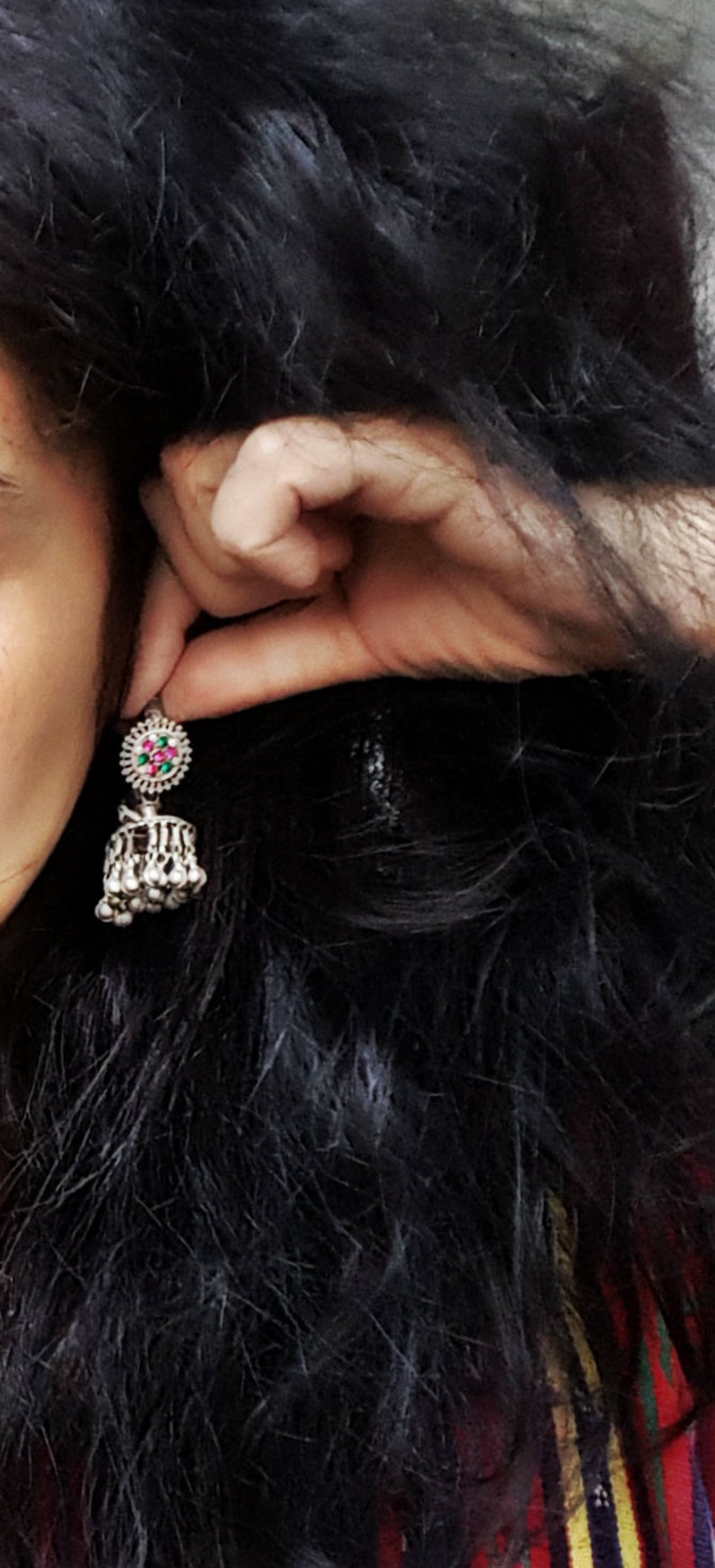 May include: A silver dangle earring with a round, multi-coloured stone and a teardrop-shaped pendant with silver beads.