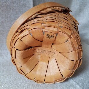Puede incluir: Una cesta tejida de color marr&oacute;n con asa. La cesta est&aacute; etiquetada con "Longaberger Baskets" y "Handwoven" con la ubicaci&oacute;n "Dresden, Ohio USA". El n&uacute;mero "509" est&aacute; escrito en la parte inferior de la cesta.
