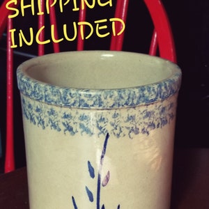 May include: A cream-colored ceramic crock with a blue and white speckled glaze. The crock has a blue and white floral design on the front. USA SHIPPING INCLUDED is written in yellow text at the top of the image.