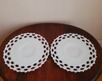 May include: Two white milk glass cake plates with a scalloped edge and a repeating pattern of holes around the rim.