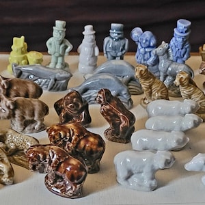 May include: A collection of 30 miniature ceramic figurines, featuring a variety of animals, people, and objects. The figurines are painted in various colors, including white, brown, blue, and green. Some of the figurines are standing, while others are sitting or lying down.
