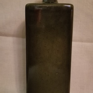 May include: A dark green ceramic vase with a square body and a simple, rounded neck.