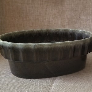 May include: A dark gray oval ceramic planter with a light gray rim and a textured surface.