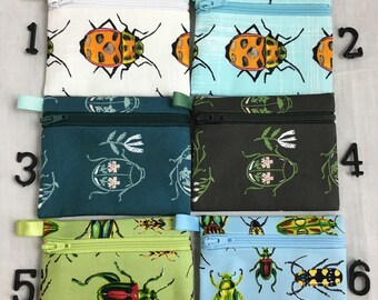 May include: Six small zippered pouches with different insect patterns. The pouches are numbered 1 through 6. The patterns include ladybugs, beetles, and other insects on white, blue, green, and black backgrounds.