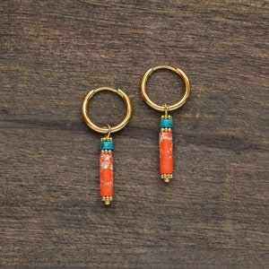 May include: A pair of gold hoop earrings with dangling charms. The charms are made of orange and turquoise beads.