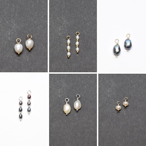 May include: Six pairs of pearl and black pearl earring charms with gold and silver findings. The charms are on a white and grey background.