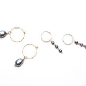May include: Three pairs of earrings with hoops and dangling pearls. Two pairs have gold hoops and one pair has silver hoops.