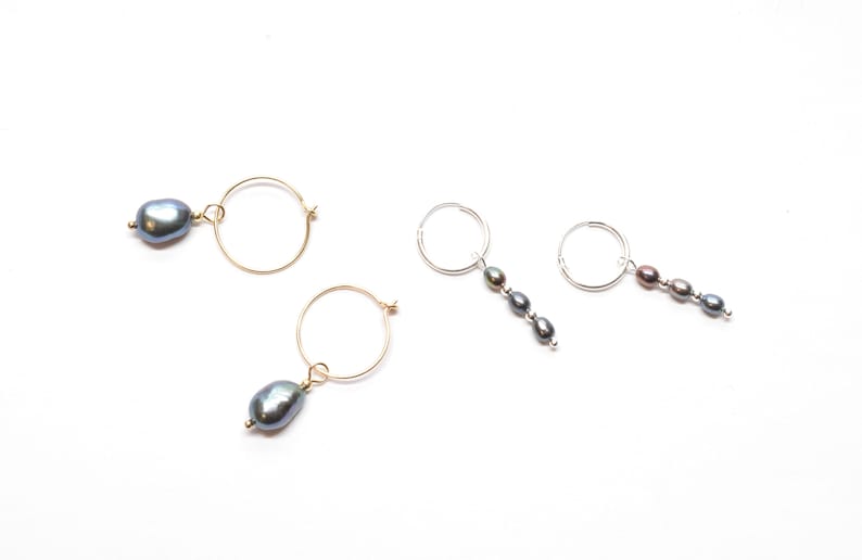May include: Three pairs of earrings with hoops and dangling pearls. Two pairs have gold hoops and one pair has silver hoops.