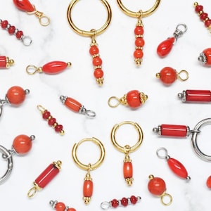 Può includere: Assortimento di perle e cerchi in corallo rosso di varie forme e dimensioni. Le perle sono infilate su cerchi d'oro e d'argento, e alcune sono attaccate a piccoli cerchi d'oro. Le perle sono tutte di un colore rosso vibrante.