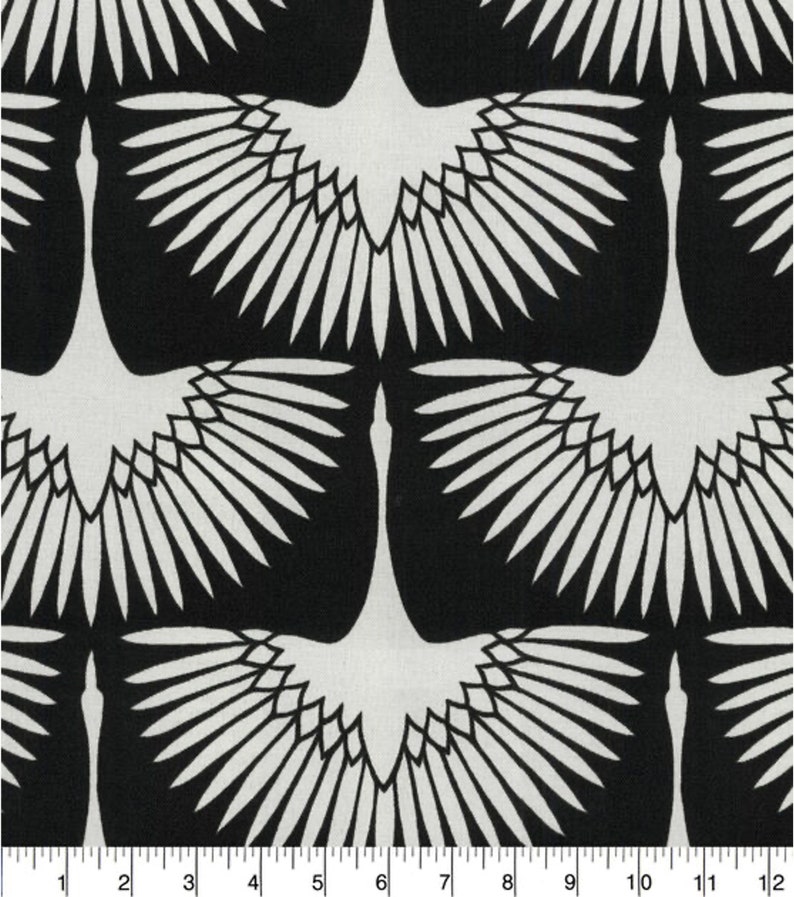 Puede incluir: Tela negra y blanca con un patr&oacute;n repetido de grullas estilizadas con las alas extendidas. Las grullas son blancas y el fondo es negro.