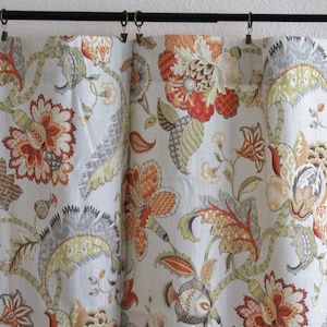 May include: Curtains featuring a floral design in shades of orange, red, green, and grey. The curtains are made from a lightweight fabric with a subtle sheen.