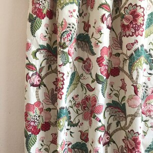 May include: White fabric curtain with a floral pattern in shades of pink, green, and brown. The pattern features large flowers and leaves.