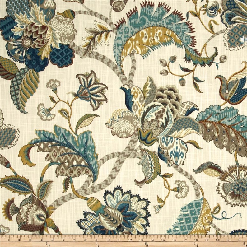 May include: A beige fabric with a blue, brown and gold floral pattern. The fabric features a repeating design of stylised flowers and leaves.