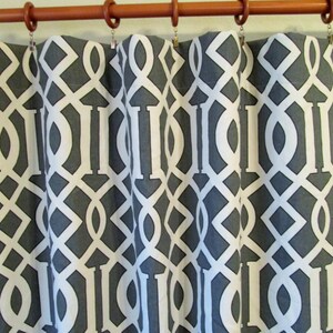 Puede incluir: Cortinas con estampado geométrico gris y blanco con una barra de cortina marrón.