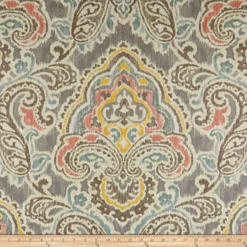 K&ouml;nnte beinhalten: Ein Stoffmuster mit einem Paisley-Muster in Graut&ouml;nen, Blau, Gelb und Rosa. Der Stoff hat einen dezenten Glanz und eine weiche Textur.