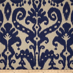 May include: A close-up of a blue and beige fabric with an ikat pattern. The fabric has a textured surface and a repeating design of swirls and diamonds.