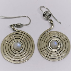 Könnte beinhalten: Ein Paar silberne Ohrringe mit einem Spiraldesign und einem weißen Mondstein in der Mitte jedes Ohrrings.
