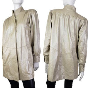 May include: A long-sleeved, light gold leather jacket with a mandarin collar and button closure. The jacket has a slightly puffed sleeve and a relaxed fit.
