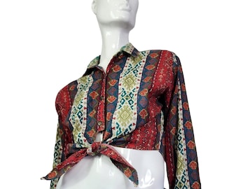 May include: A red, green, and blue patterned long-sleeve shirt with a tie at the waist. The shirt is tied in a knot at the front.