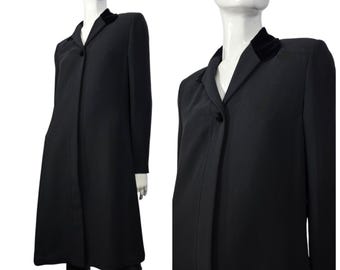 May include: A long, black coat with a velvet collar and a single-button closure. The coat is displayed on a mannequin, showcasing its tailored design and length. The coat's sleek silhouette suggests a classic, elegant style.