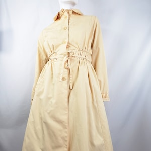 May include: A long-sleeved, light yellow trench coat with a cinched waist and a button-up front.