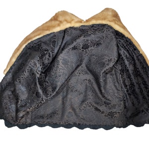 May include: A brown fur coat with a black floral lining. The coat has a large collar and a scalloped hem.