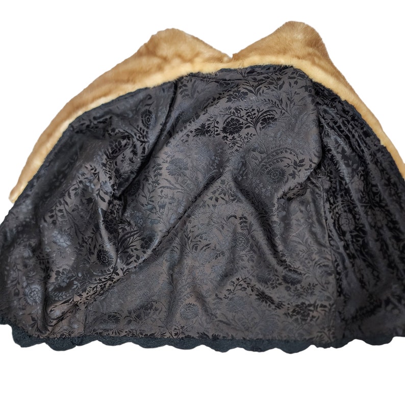 May include: A brown fur coat with a black floral lining. The coat has a large collar and a scalloped hem.