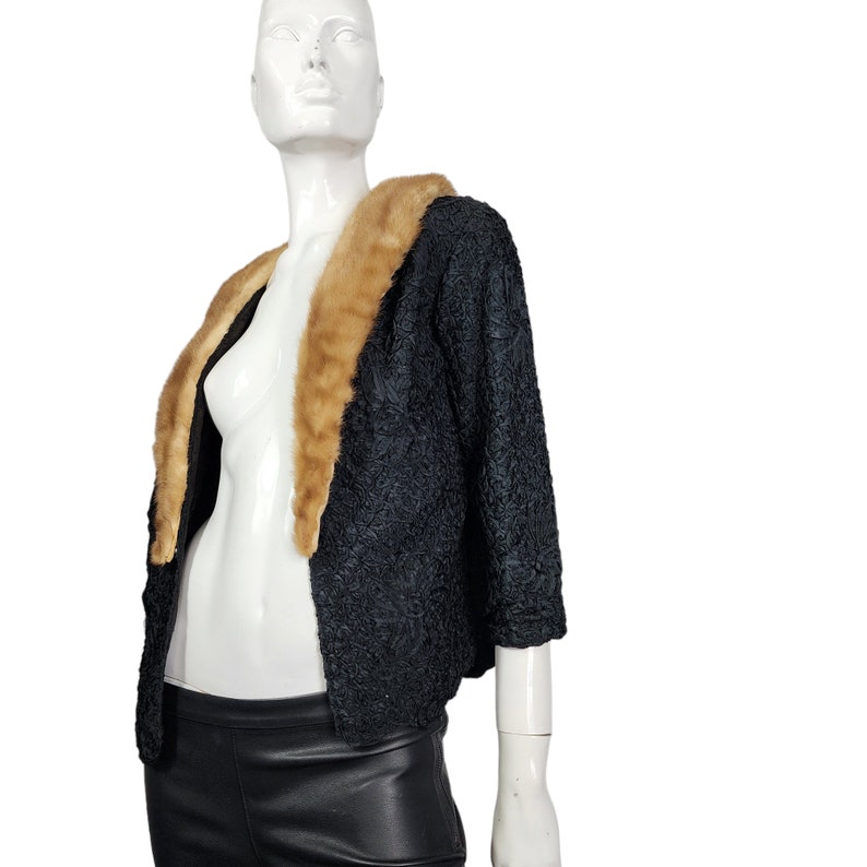 May include: A black, textured, cropped jacket with a large, brown fur collar.