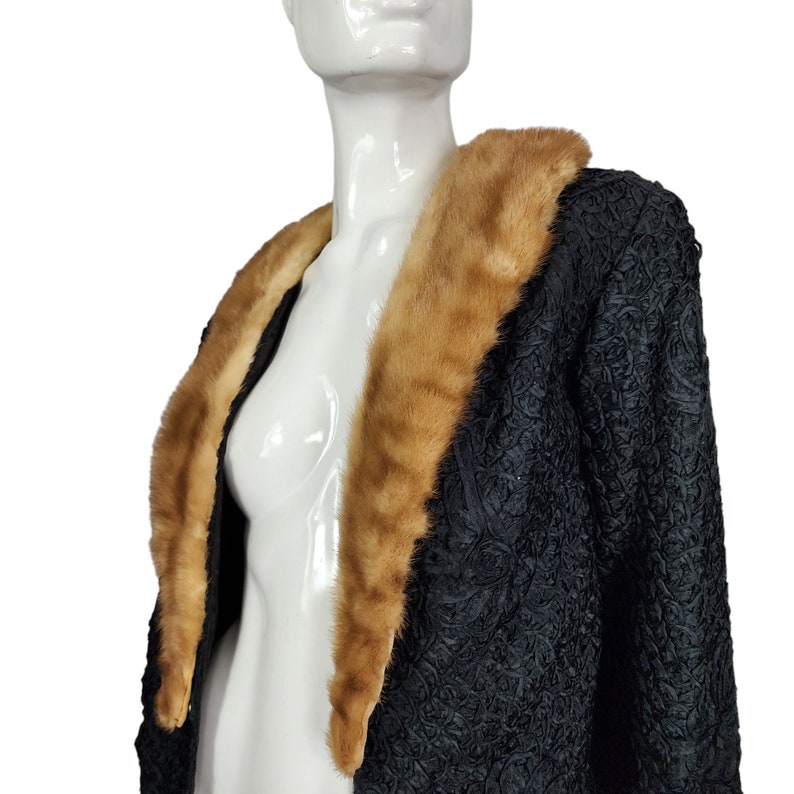 May include: A black, textured jacket with a large brown fur collar. The jacket is on a white mannequin.