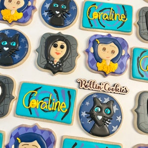 May include: A set of decorated sugar cookies featuring characters and themes from the movie Coraline. The cookies are decorated with blue, purple, yellow, black, and white icing. The cookies feature the text "Coraline" and "Rollin' Cookies".