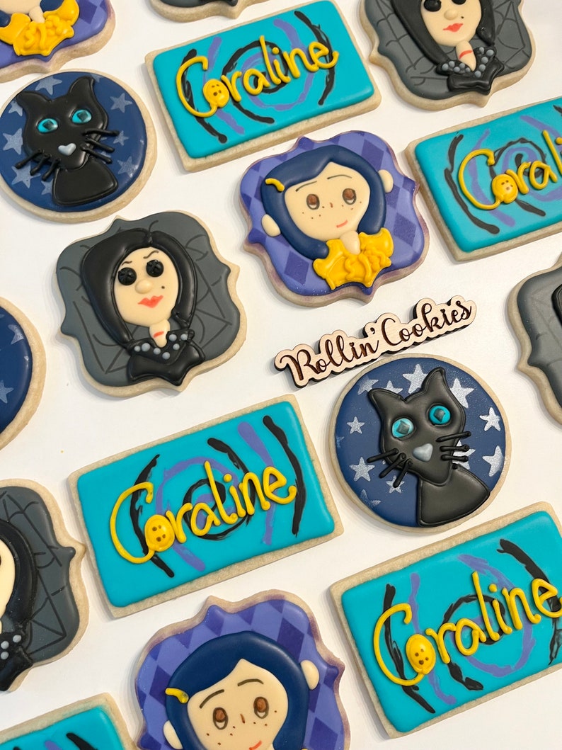 May include: A set of decorated sugar cookies featuring characters and themes from the movie Coraline. The cookies are decorated with colorful icing and include images of Coraline, the Other Mother, and the black cat.