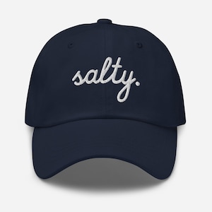 May include: Navy blue baseball cap with the word "salty" embroidered in white script across the front. The cap has a curved brim and a button on top.