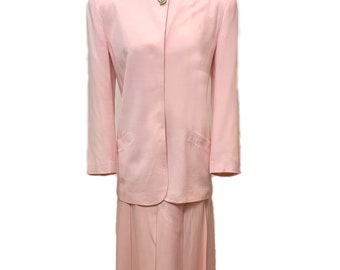 May include: A pink skirt suit with a long skirt and a matching jacket. The jacket has a single button closure and a small pocket on each side. The skirt has pleats and falls to the knees.