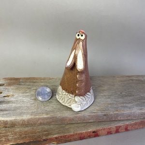 May include: A ceramic rabbit figurine with brown and white glaze. The rabbit has large eyes and a pink nose. The base of the figurine is decorated with white leaves.