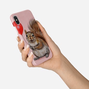 May include: A pink iPhone case with a cute illustration of a squirrel holding a red balloon.